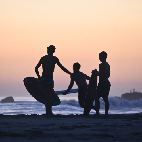 Skimboarders al atardecer en la playa